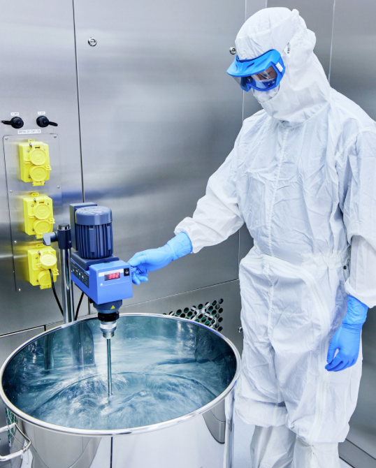 A worker in a white clean suit mixing liquid